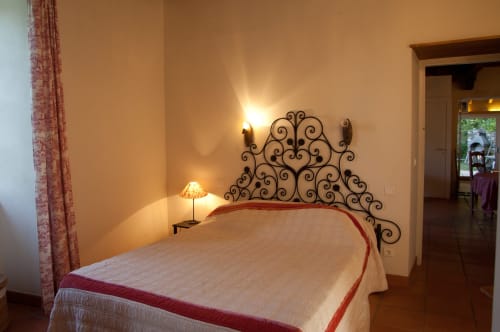 Chambre avec tête de lit en fer forgé ouvragé aux Chambres d'hôtes Les Pratges, Figeac, vue sur jardin et lampe de chevet