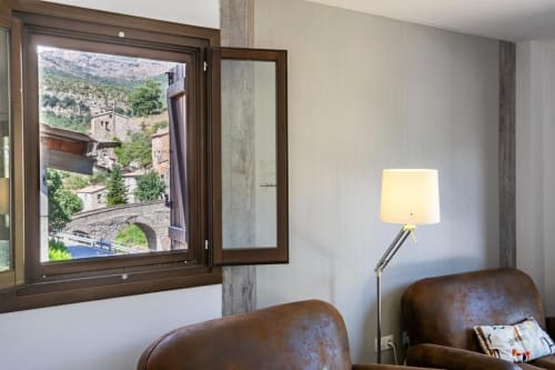 Moderno interior de apartamento con sillones de cuero marrón, lámpara de pie y ventana con vistas a pueblo montañoso en Montgat