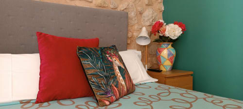 Elegante habitación doble en Pensión Alicante San Nicolás con almohadas rojas, ropa de cama estampada y pared de acento turquesa