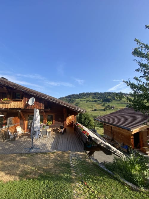 Chalet en bois avec terrasse ensoleillée dominant une vallée alpine verdoyante, Notre-Dame-de-Bellecombe
