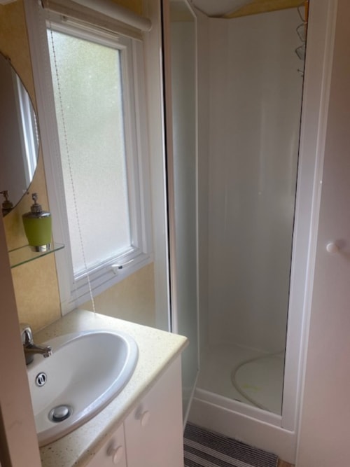 Salle de bain compacte de la villa Auvergne du camping Le Relais de La Mirpe, Bergerac, avec lavabo rond et cabine de douche