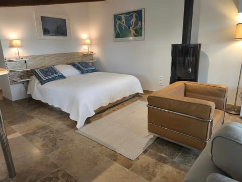 Chambre élégante à la Magnanerie de Sainte Croix avec lit queen-size, fauteuil en cuir biscuit et sol en ardoise à Saint Hippolyte de
