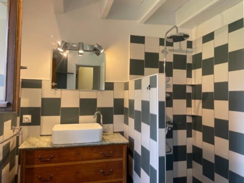 Salle de bain moderne au Château de Vaux Morvan avec carreaux damier noir et crème, vasque en bois et douche à effet pluie