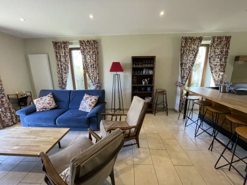 Spacieux salon du Château de Vaux Morvan avec canapé bleu, sièges confortables et vue sur le jardin