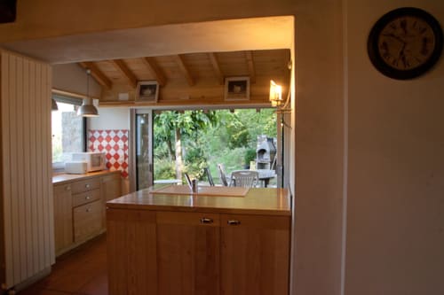 Cuisine chaleureuse en bois avec comptoir ouvert sur le jardin au gîte Les Pratges, Figeac