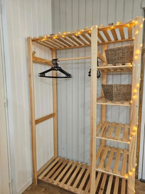 Armoire en bois avec portant, paniers tressés et guirlandes lumineuses dans l'appartement L'or Noir aux Gîtes Saint Valéry En Caux