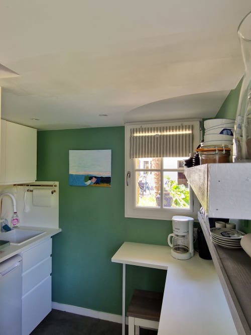 Cuisine lumineuse de la Suite Familiale aux Chambres du Keriolet avec murs verts, plans de travail blancs, cafetière et jardin