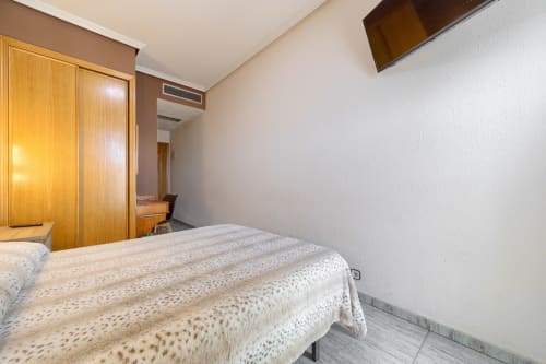 Habitación luminosa en el Hostal El Molino de Collado Villalba con cama doble, armario de madera y paredes blancas