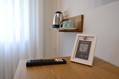 Escritorio de la habitación con marco de código QR WiFi y panel de control en Hotel Boutique Alcazaba Salobreña
