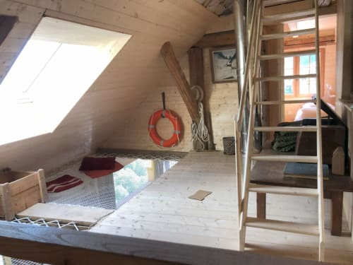 Cozy attic loft bedroom at Les Chalets de l'Eau Rousse with wooden beams, skylight, ladder access, and mountain views in