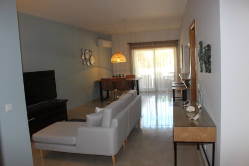 Seahorse House apartment living area with white sofa, dining table, and pool view at Break Lovers, Tavira