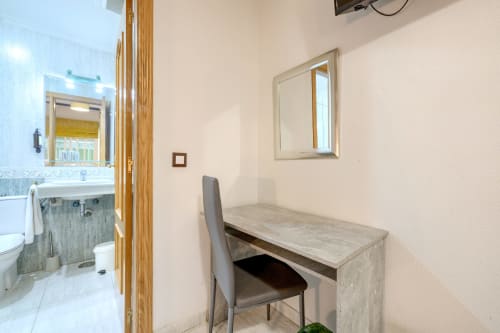 Habitación Doble Interior en Hostal El Molino en Collado Villalba con escritorio, silla, espejo y entrada al baño