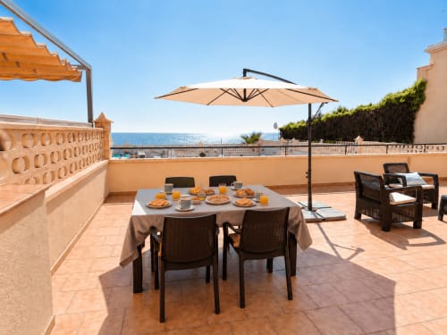 Beachfront terrace at Apartamentos El Calón Playa with dining table, umbrella, and sea views in Cuevas del Almanzora