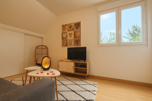 Séjour cosy avec télévision, meubles en bois, décoration cœur et vue sur la ville aux Gîtes Saint Valéry-en-Caux