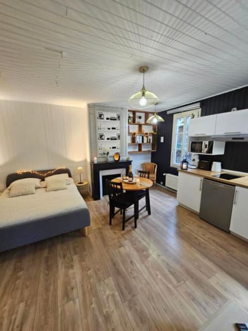 Studio moderne aux Gîtes Saint Valéry-en-Caux avec lit, cuisine, salle à manger et murs d'accent foncés