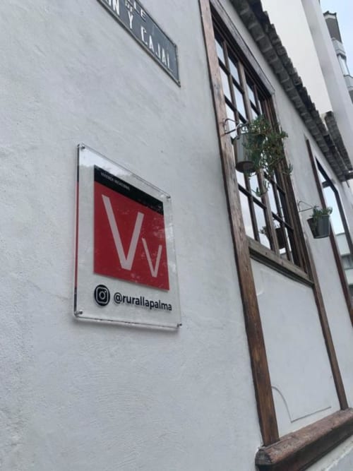 Cartel Rural La Palma en fachada blanca con ventana de madera y plantas colgantes en Santa Cruz de la Palma