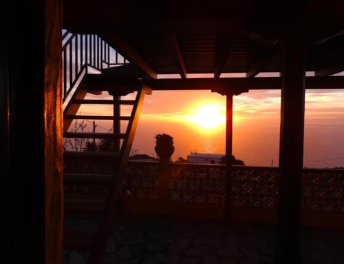 Espectacular vista del atardecer desde la terraza de Villa Las Flores en Tijarafe, La Palma, con horizonte oceánico enmarcado por arquitectura de madera