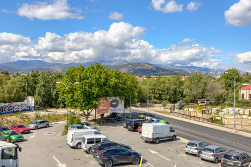 Estacionamiento del Hostal El Molino en Collado Villalba con montañas y cielo azul al fondo