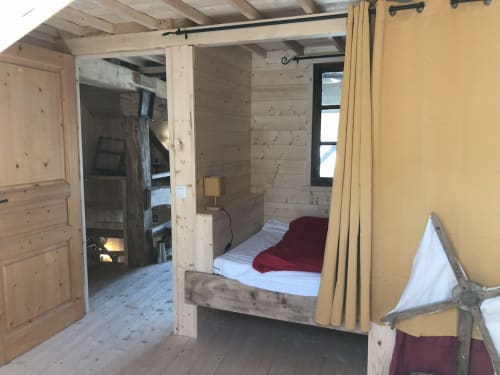 Cozy bedroom at Les Chalets de l'Eau Rousse in Celliers with wooden beams, bed with burgundy blanket, yellow curtains
