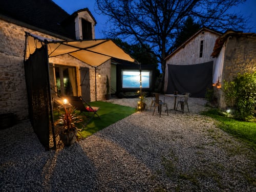 Cour de Domaine Valenquercy au crépuscule avec écran de cinéma privé, salon de détente et auvent ambré