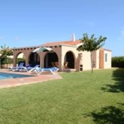 Villa Las Golondrinas en Cap d'Artrutx con piscina, terraza, tumbonas azules, jardín cuidado y arquitectura mediterránea