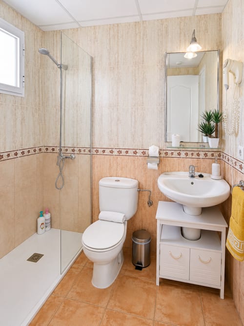 Modern bathroom at El Calón Playa apartment with walk-in shower, white fixtures, and beige tile walls