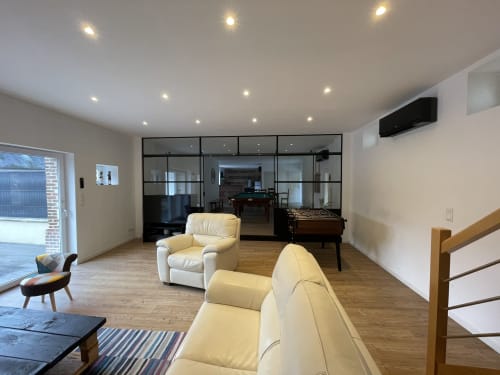 Modern cottage living area at Les Gites De Flaubert with cream furniture, foosball table, and glass partition to game room