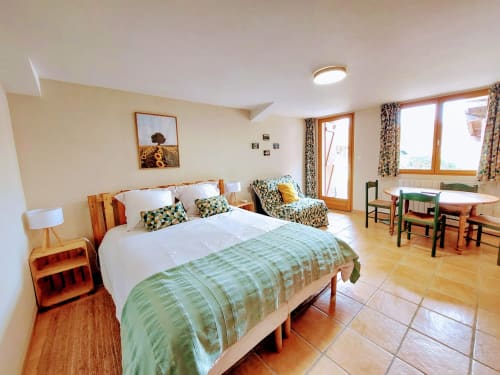 Bright bedroom in Sunflowers cottage at Les Gites de Campardon with double bed, seating area, and garden view windows in