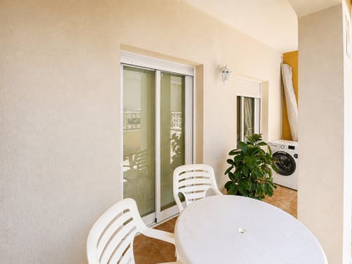 Espacio luminoso en Apartamentos El Calón Playa con mesa de comedor blanca, puertas correderas de vidrio y zona de lavandería