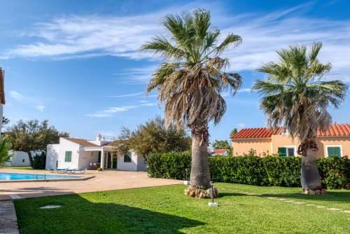 Villa Las Golondrinas con palmeras, piscina y jardín cuidado en Cap d'Artrutx, Menorca
