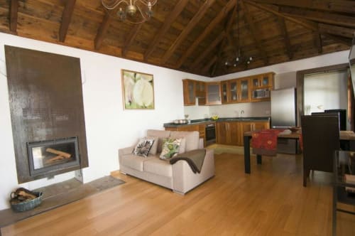 Sala de estar de Villa Awara con chimenea, sofá beige, vigas de madera, cocina y suelos de madera en La Palma rural