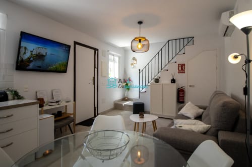 La moderna sala de estar de Casa LirioBanco con escalera, sofá gris, TV y mobiliario contemporáneo en de las