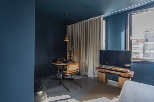 Moderno apartamento hoteleiro no Porto com paredes azuis, mesa de madeira, cadeira de vime, TV de tela plana e cortinas do piso ao teto