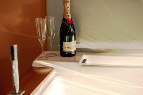 Bouteille de champagne Moët & Chandon avec deux flutes vides sur la table de nuit d'un loft de luxe à Saint-Valery-en-Caux