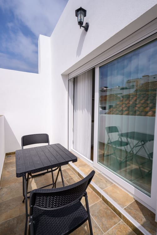 Terraza privada del Hotel Alcazaba Salobreña con mesa negra, sillas y vistas a la Alcazaba de Granada, España