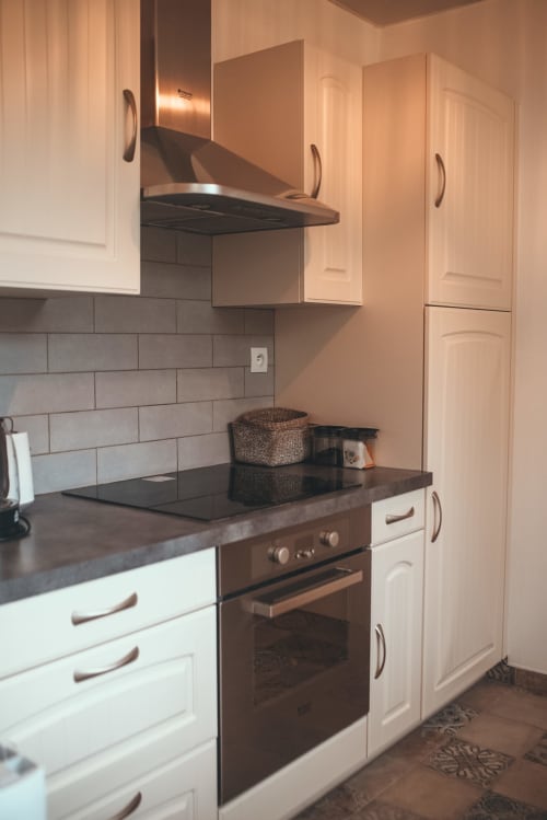 Cuisine moderne du cottage Bobochic à ART DE VOYAGER, Étretat avec mobilier blanc, plan de travail foncé et acier inoxydable