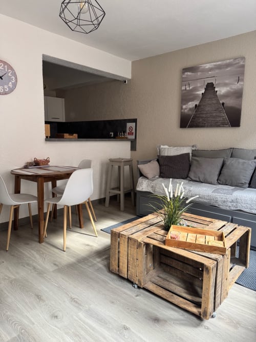 Studio moderne à Troyes avec séjour, table à manger, canapé gris, table basse en bois et kitchenette noire