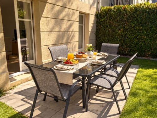 Espace repas en jardin au Paradis Des Logis avec table dressée, chaises et végétation luxuriante à Pierrefitte sur Seine