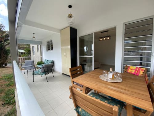 Salle à manger de l'appartement vue jardin à Kay Betty, Martinique avec table en bois, cuisine moderne et places assises confortables.