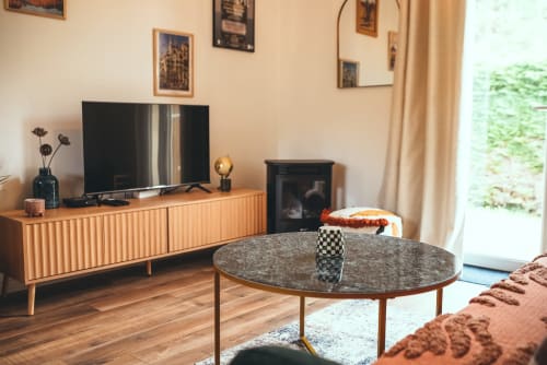 Salon moderne du gîte d'Étretat avec télévision, cheminée, table marbre ronde et vue sur le jardin