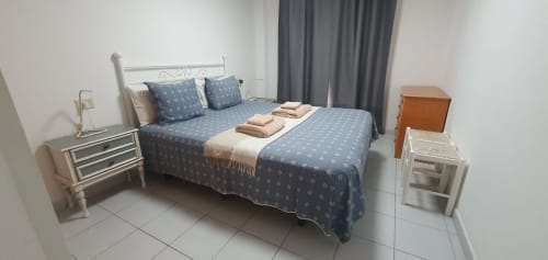 Modernes Schlafzimmer im Alquila en Canarias El Médano mit Queensize-Bett, blauer Bettwäsche, Nachttischen und Stadtblick.