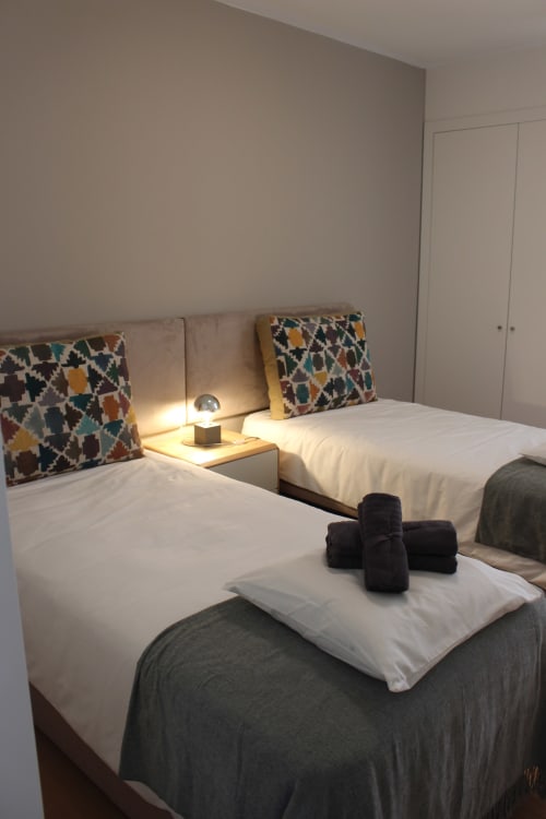 Twin beds at Break Lovers seaside apartment in Tavira with colorful pillows and bundled towels