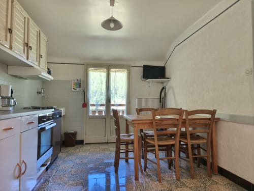 Cucina e zona pranzo dell'Appartamento 4, Chalet Coste Belle, Ceillac con tavolo in legno e accesso al balcone con vista montagna