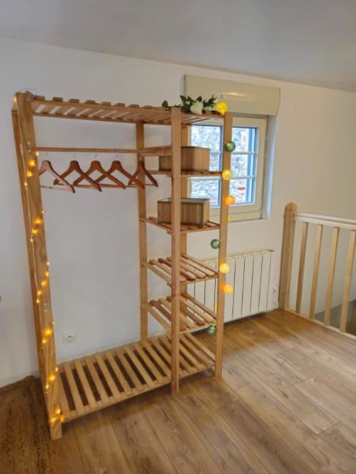 Armoire en bois avec penderie, étagères et guirlande de décoration dans l'appartement Sous les Toits aux Gîtes Saint Valery En