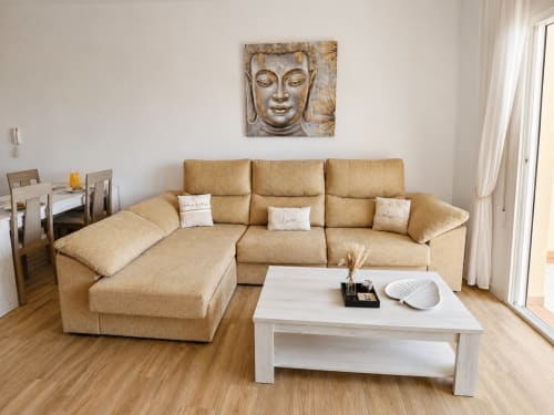 Beige sectional sofa with white coffee table in sunny living room of El Calón Playa apartment