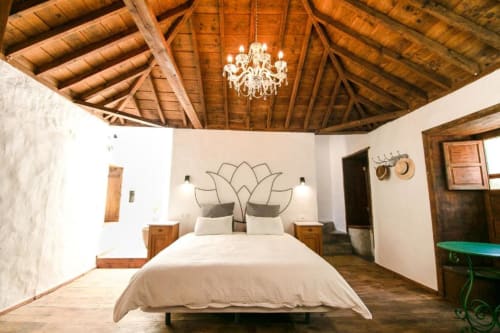 Espacioso dormitorio en Casa 1820 con vigas de madera vista, araña de cristal, cabecero decorado con arte de flor de loto