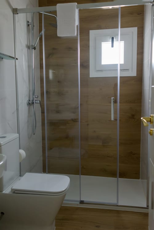 Moderno box de ducha de vidrio con revestimiento tipo madera en baño del Hotel Boutique Alcazaba Salobrena