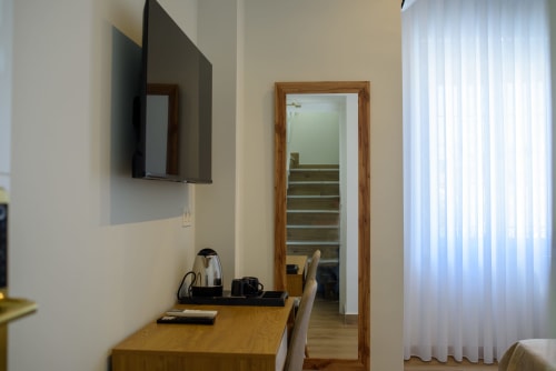 Habitación moderna de hotel en Alcazaba Salobrena con TV montada en pared, escritorio de madera y acceso a escalera por puerta de cristal