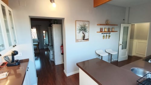 Cocina moderna del apartamento Mirador Medieval en Cáceres con encimeras de madera, paredes blancas y pisos de madera oscura