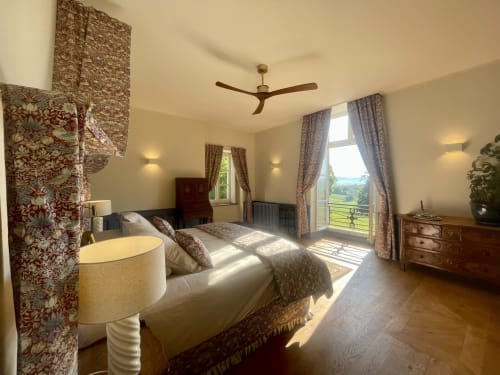 Chambre élégante au Château de Vaux Morvan avec vue sur le jardin, lit à parure motifs, ventilateur plafond